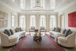 Modern living room with white sofas, a red rug,  coffee table, and decorative elements.