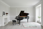 Black grand piano in a white room with decorative rug