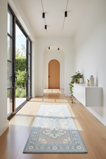 Modern interior with a blue patterned rug on wooden flooring, large glass door, and white walls.