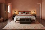 Bedroom with pink walls, wooden bed, and decorative rug.