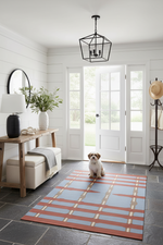 Dog sitting on a patterned rug in a modern living room with a white door and wooden furniture.