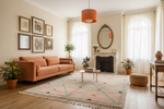 A styled living room featuring a terracotta orange sofa, a matching orange pendant light, a pink and green patterned rug, and a white fireplace with a mirror.