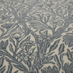 Close-up of a woven textile with an allover floral and botanical pattern in dark blue-gray on a warm cream background.