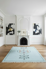 Living room with a light blue rug, white fireplace, and abstract art on the walls.