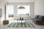 A modern living room with a dark gray sofa, a round black coffee table, a green and white geometric patterned rug, and a woven pendant light hanging from the ceiling.