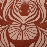 A close-up of a textured rug featuring a stylized floral and abstract pattern in terracotta red and light beige.