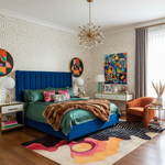 Modern bedroom with blue bed, colorful rug, and abstract art