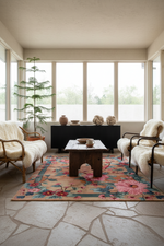 Living room with floral rug, wooden coffee table, and armchairs.