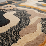 Close-up of a textured area rug with an abstract organic pattern in beige, cream, charcoal, and mustard yellow.