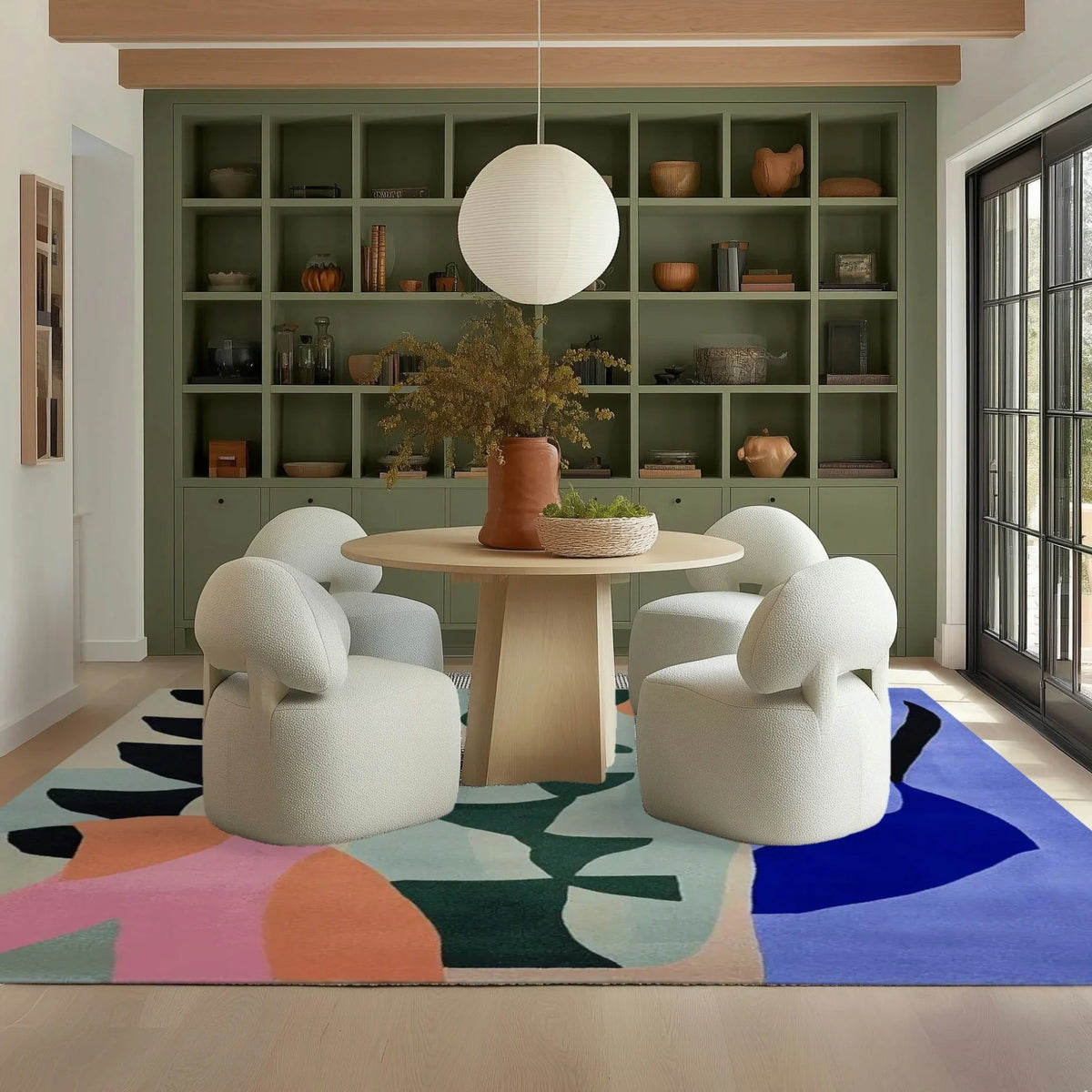Modern living room with white chairs, round table, and colorful rug.