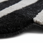 Close-up of a black and off-white striped textured rug, showing the thick pile and frayed edges against a white background.