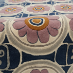 Close-up of a textured area rug with a mid-century modern floral pattern in pink, navy blue, beige, and mustard yellow.