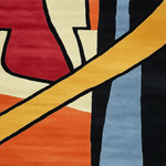 Abstract geometric patterned textile close-up with bold blocks of red, cream, orange, yellow, black, and light blue separated by thick black lines.