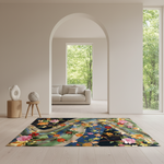 A rectangular area rug with a vibrant, multicolored floral and bird pattern is displayed on a light wood floor in a modern, minimalist living room. The room features a large arched doorway leading to a light gray sofa and a lush green outdoor view.