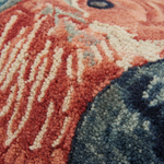Close-up of a textured area rug with a chunky looped pile, featuring a pattern of terracotta, cream, slate blue, and navy.