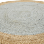 A close-up of a round woven rug with a light gray center and a natural tan braided border.