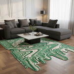 A modern living room scene featuring a large area rug with a green and cream wavy, fluid-like pattern. The rug is styled on a light wood herringbone floor under a dark gray sectional sofa and a white marble-top coffee table.
