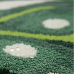 Close-up of a green textured rug or carpet with bright lime-green curved stripes and white circular accents, showing water droplets on the surface.