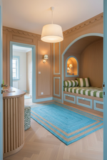 A beautifully styled interior room with warm wood paneling, a built-in daybed with green and white striped cushions, a bright blue rug, and a ribbed white pendant light hanging from the ceiling.