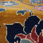 Close-up of a plush area rug with a floral pattern in mustard yellow, navy blue, red, light blue, and cream.