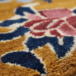 Close-up of a plush patterned rug with mustard yellow, navy blue, pink, and cream sections.