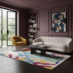 A styled living room interior with a cream curved sofa, mustard yellow armchair, dark wood coffee table, and a large abstract multicolor area rug on dark wood flooring. The room features deep plum paneled walls, built-in shelving, and a glass door opening to a garden.