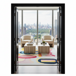 A modern interior scene viewed through open black-framed doors, showing a furnished room with two cream armchairs, two striped coffee tables, a colorful abstract area rug, and a large floor-to-ceiling window overlooking a city skyline and green park.