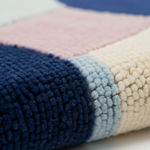 Close-up of a chunky knit blanket with color-blocked sections of navy blue, light pink, pale blue, and cream.