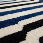 Close-up of a textured rug with a geometric pattern of thick horizontal stripes in blue, cream, and black.