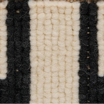 Close-up of a textured woven rug or textile with alternating thick vertical stripes in off-white/cream and black.