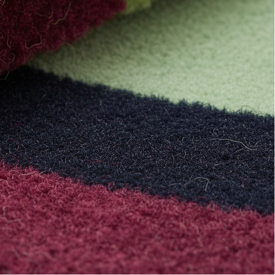 Rolled corner of the Maia Burgundy Geometric rug showing burgundy, navy, and sage striped bands