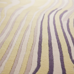 A close-up of a textured area rug with a modern wavy pattern in pale yellow, cream, and muted lavender-purple.