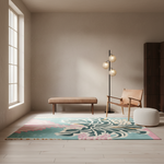 A large rectangular area rug with a teal, pink, and cream floral pattern is styled in a minimalist room with a wooden floor, a beige wall, a bench, a floor lamp, and a chair.