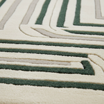 Close-up of a plush area rug with a modern geometric pattern of concentric arches and stripes in dark green, beige, and cream.