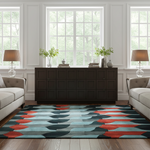 A modern area rug with a geometric pattern of teal, red, and dark gray abstract shapes, styled in a bright, contemporary living room with a dark wood credenza, sofas, and lamps.