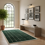 A dark green area rug with a cream geometric grid pattern is styled in a modern, warm-toned living room next to a large arched window, a stone bench, and framed black-and-white portraits.