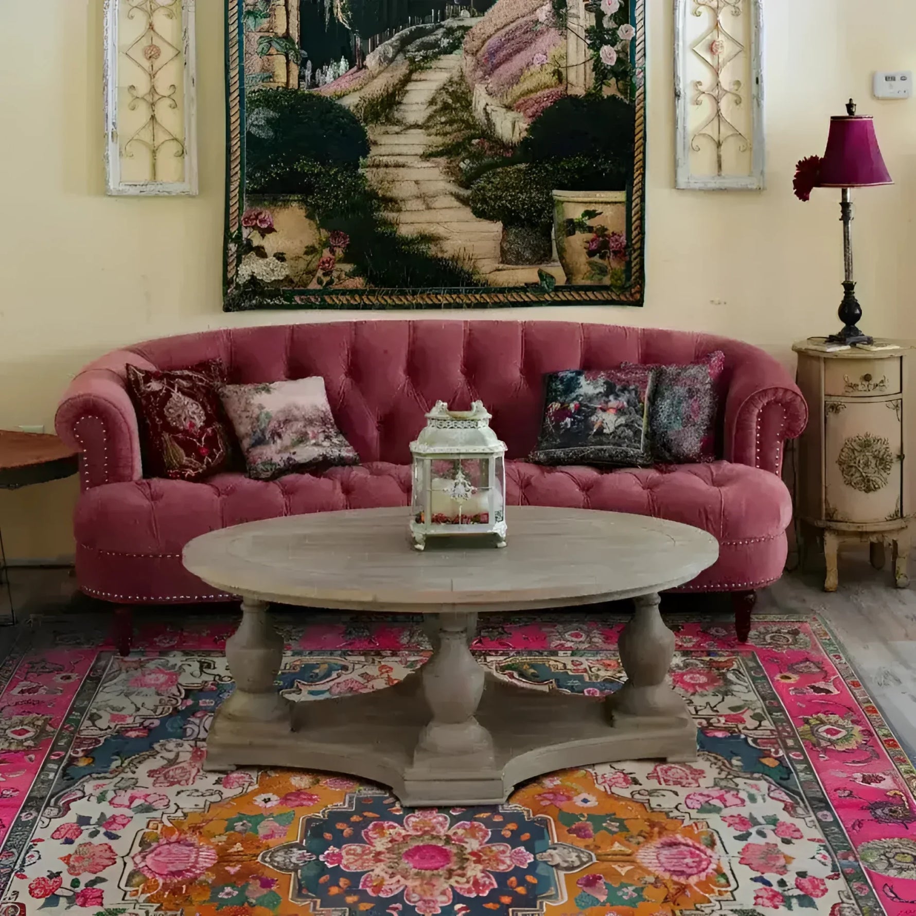 Pink sofa with decorative pillows in a room with a colorful rug and wall tapestry.
