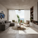 A modern, sunlit living room with a gray sectional sofa, two wooden chairs, a round patterned rug, a low coffee table, and a large window looking out to the ocean. A blue car artwork hangs on the wall, and the room is styled with neutral tones and natural light.
