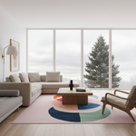 A modern living room with a light beige sectional sofa, a wooden coffee table, a pink area rug with a large multicolor circular pattern, and a wooden armchair. Large floor-to-ceiling windows show a snowy evergreen tree outside.