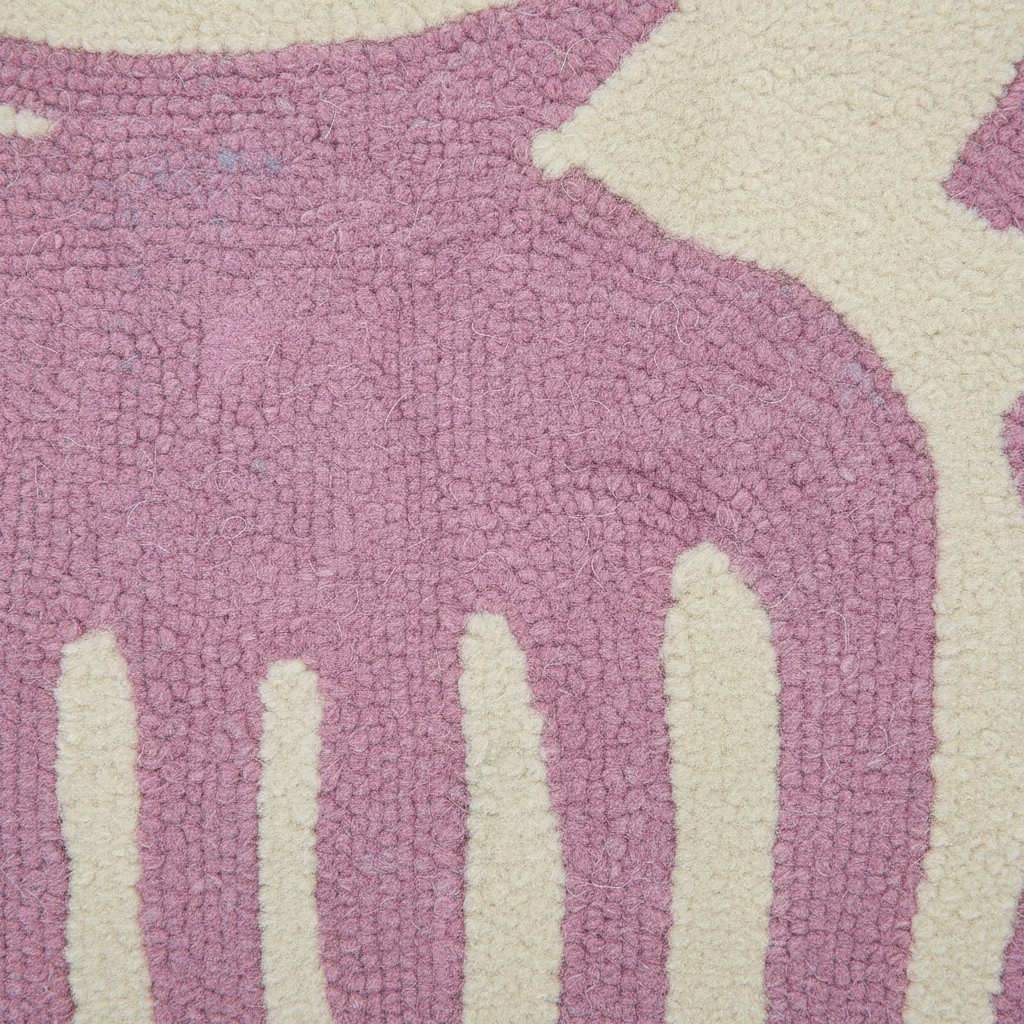 A close-up of a textured, looped pile rug featuring a large dusty pink abstract shape over an off-white background.