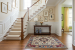 Staircase with wooden banister, floral rug, and decorative items in a home interior.