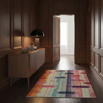 A colorful abstract-patterned area rug lies on a dark wood floor in a classic hallway with wood-paneled walls, a wooden sideboard, and a lit lamp.