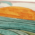 Close-up of a colorful textured rug featuring a large orange sun and layered teal, green, and pink landscape shapes.