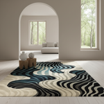 A rectangular area rug with a wavy, flowing abstract pattern in black, navy, teal, gray, and cream, styled in a bright, modern living room with light wood floors and an arched doorway.