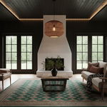 A styled living room interior with dark wood paneled walls and ceiling, a large white fireplace surround, French doors, a patterned green and beige rug, a wooden coffee table, and a woven pendant light hanging above the fireplace.