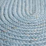 A close-up of a light blue braided rug or mat showing the detailed woven texture.