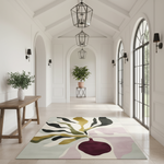 A large area rug with an abstract botanical design in muted green, mustard, burgundy, and blush pink tones, displayed in a bright, modern hallway with arched doorways and pendant lights.