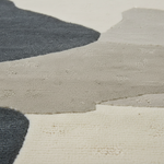 Close-up of a textured area rug with an abstract organic pattern in cream, light beige, and dark charcoal gray.
