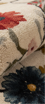 Close-up of a plush area rug with a floral pattern, showing a cream base with red, navy, olive green, and pink flowers.