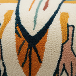 Close-up of a textured, loop-pile rug with an abstract geometric pattern in orange, mustard yellow, dark navy, cream, and dusty pink.